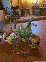 Photo showing several wicker and plastic laundry baskets along with metal wire racks and the base of a coat stand on the floor