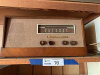 Front view of wooden cabinet radio with fabric front and four knobs and tuning dial window