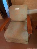 Front view of the green upholstered armchair with subtle orange leaf pattern, wooden arms visible, cushion and backrest shown.