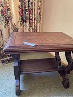 Side view of wooden side table showing the built-in lower shelf/magazine rack and decorative legs