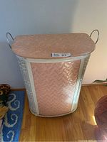 Front view of the tall vintage clothes hamper showing curved wicker base and pink vinyl panel.