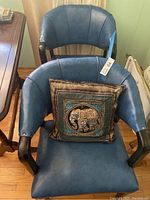 Front view of one blue leather club chair with silk pillow featuring elephant design on the seat.
