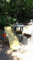 Vintage outdoor folding chairs, round plastic table, vintage picnic case, and accessories including blanket, small fold-up side table, and thermos.
