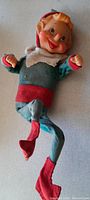 Front angled view of the elf showing its smiling face, red waistband, and curled red shoes