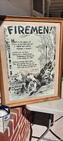 Framed 1947 Firemen poster by Nick Kenny displayed upright in natural light showing full artwork, poem, and signature with wooden frame.