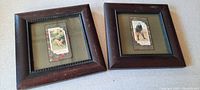 Two framed golf sports cards under glass with wooden frames, lying flat on a surface.