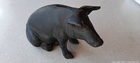 Side profile of the black cast iron pig bank showing details of the snout, ears, and general shape.
