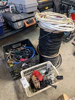 Overview of lot showing two crates with multiple small cables and two large spools of cable, one black and one white.