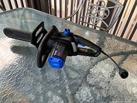 Chainsaw shown from top and side angles with protective blade cover and power cord.