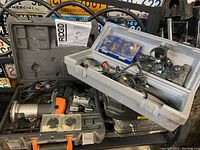 Ridgid laminate trimmer and Dremel rotary tool with cases and accessories on shelf.