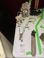 Photo showing elephant figurine, crocodile figurine with chipped trunk, rhinoceros figurine, and part of the metal incense holder on a white table.