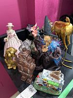 Photo showing assorted figurines including Halloween witch, golden monkey, golden deer, and angel figurine.