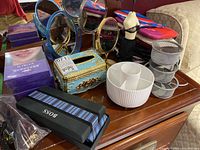 Overall view of mirrors, tissue box, facial masks, makeup bags, tie and cuff links on wooden table