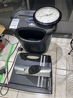Photo showing Fellowes shredder, paper cutter, hole punch and round wall clock on tiled floor