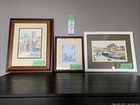 Three framed artworks on display - York Minster by P.B. Rennison and two coastal/harbor scenes by Grahame Penn