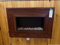Front view of Bionaire wall fireplace, showing woodgrain frame and decorative glass embers inside.