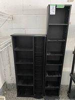 Full view of the black shelving unit featuring multiple shelves and a cylindrical CD storage tower in the middle.