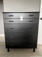 Front view of black 5-drawer dresser showing all drawers and integrated black handles.