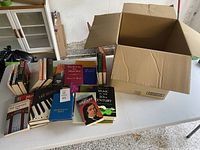 Box of books shown on table with some titles visible including Music in the 20th Century and Oscar Levant biography.
