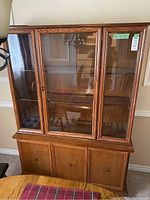 Full view of the wooden buffet and hutch showing front three glass doors in the hutch portion and four lower cabinet doors.