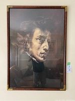 Framed portrait of Chopin displayed on a wall with visible wooden and metal frame elements.