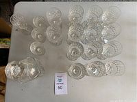 Top view of decanter and 12 glasses arranged on a table, showing starburst and crosscut patterns
