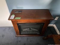 Front view of the plug-in electric fireplace showing the wood finished cabinet and fireplace insert with faux logs.