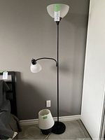 Full view of black floor lamp with two lights and a black table lamp base with white lampshade detached on the floor