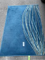 Blue IKEA rug with beige leaf pattern and a size label indicating approximately 132x195 cm