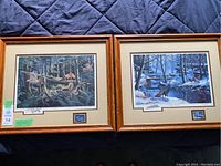 Two framed prints side by side on a blue quilted surface, both attributed to Ken Zylla with wood frames and cream matting.