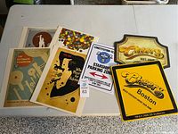 Entire lot displayed on a table showing two metal Cheers signs, one Star Trek sign, and four posters.