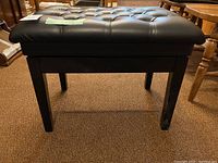Side view of black padded adjustable stool showing tufted cushion seat, wooden legs, and adjustment knob on side.