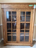 Front view of oak shelving unit with two glass pane doors and wooden grid design