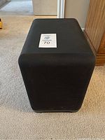 Front view of black cube subwoofer with lot tag.