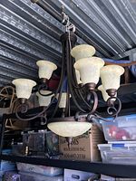 Full view of the large chandelier showing six alabaster shades and central alabaster bowl light on an iron frame