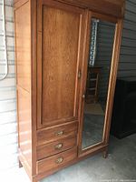 Full view of the wardrobe showing wooden paneled door, mirrored door, and 3 drawers with brass handles.