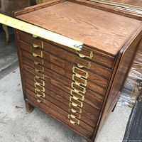 Front view showing two columns of eight shallow drawers with brass label holders and finger pulls