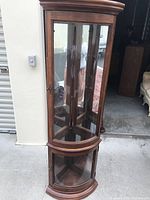 Front view of wood corner curio cabinet with glass panels and doors showing overall condition and style.