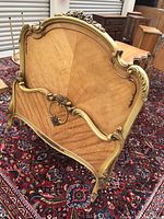 Photo of the twin bed frame showing front side of the headboard and footboard with carved gold details and wood veneer pattern on carpet.