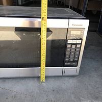Front view of Panasonic microwave with tape measure showing height at about 12.5 inches.
