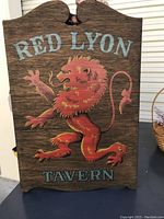 Front view of the wooden sign with the red lion and lettering.