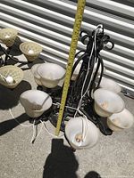 Photo showing two alabaster chandeliers side by side. Each chandelier has five alabaster bowl-shaped shades with decorative lattice patterns and dark metal frames. Measuring tape indicating chandelier height around 25 inches.