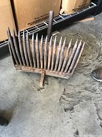 Front view of vintage wooden magazine rack with vertical pointed slats placed on concrete floor.