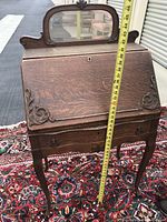 Front view of vintage wooden secretary desk with measuring tape showing height (~40 inches). Mirror mounted on top and carved details visible.