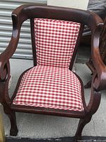 Front view of wood side chair showing red and white check upholstery on seat and backrest, carved arms and clawed feet design.