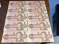 Front side of ten Canadian $2 bills arranged in two columns of five bills showing Queen Elizabeth II.