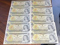 Front side of ten uncirculated Canadian one dollar bills showing Queen Elizabeth II and denomination details.
