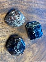 Photo of three large boulder garnet stones arranged on wooden surface showing their color and texture