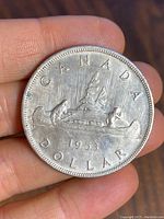 Reverse side of the 1953 Canadian silver dollar showing canoe and inscriptions including the year 1953.