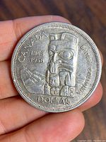Front side of the 1958 Canadian silver dollar coin showing British Columbia totem pole and inscriptions.